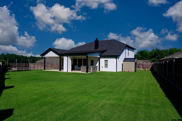 rear view of property with a lawn, a trampoline, ceiling fan, a storage unit, and a patio