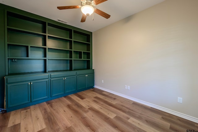 interior space featuring built in shelves, light wood-type flooring, and ceiling fan