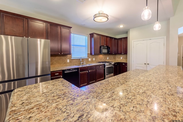 kitchen featuring light stone counters, hanging light fixtures, black appliances, and sink