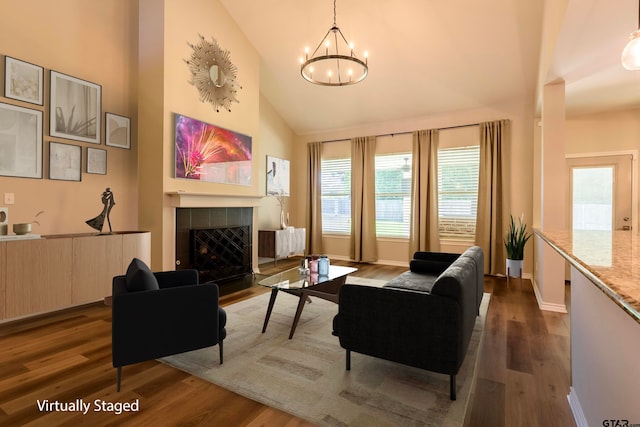 living room with a fireplace, high vaulted ceiling, dark wood-type flooring, and a notable chandelier