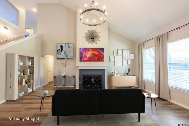 living room with a chandelier, hardwood / wood-style floors, a healthy amount of sunlight, and a tiled fireplace