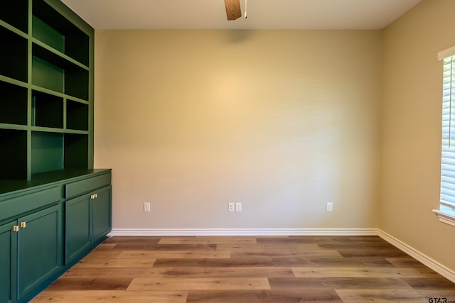 spare room featuring ceiling fan, built in features, and light wood-type flooring