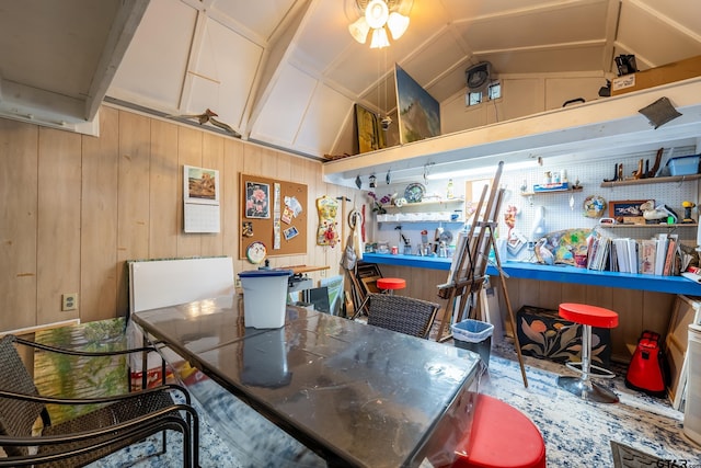 dining room featuring a workshop area, wood walls, and lofted ceiling