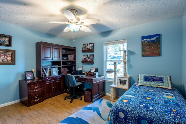 bedroom featuring ceiling fan, light wood-type flooring, and a textured ceiling