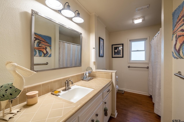 bathroom with tasteful backsplash, crown molding, wood-type flooring, toilet, and vanity