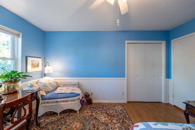 bedroom with a closet, a textured ceiling, hardwood / wood-style flooring, and ceiling fan