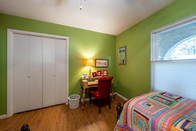 bedroom with a textured ceiling, light hardwood / wood-style flooring, and a closet