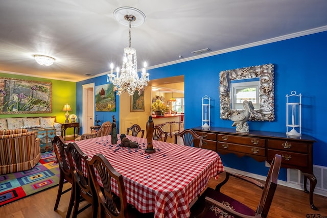 dining room with hardwood / wood-style flooring, a notable chandelier, and crown molding