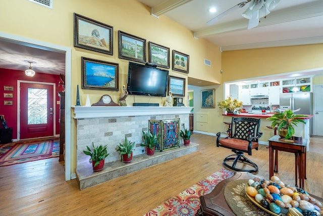 living room featuring lofted ceiling with beams, ceiling fan, and light hardwood / wood-style floors