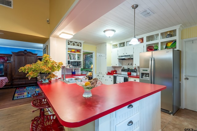 kitchen featuring a kitchen breakfast bar, sink, decorative light fixtures, white cabinetry, and stainless steel appliances