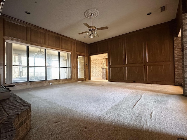 unfurnished room with carpet floors, visible vents, a decorative wall, ceiling fan, and wooden walls