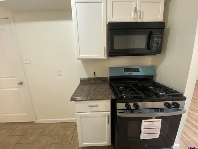 3903 Appletree Ln, Tyler, TX 75701 - kitchen with gas stove, black microwave, white cabinets, and dark stone counters