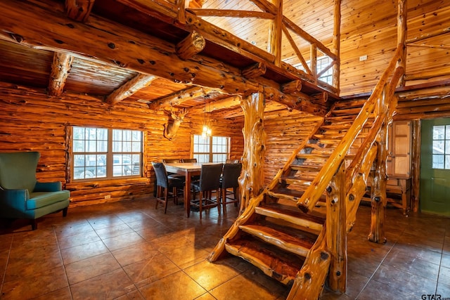 interior space with a towering ceiling, beamed ceiling, rustic walls, wood ceiling, and tile patterned floors