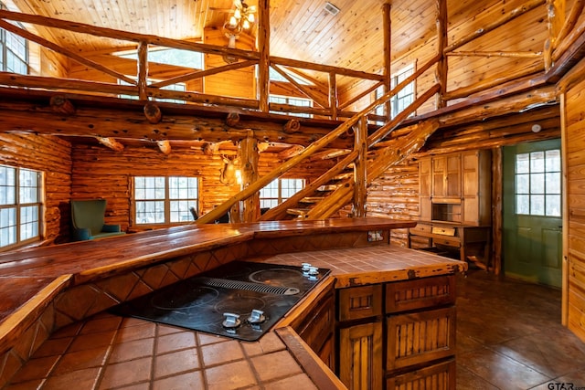 kitchen with black electric stovetop, tile counters, wooden ceiling, and high vaulted ceiling