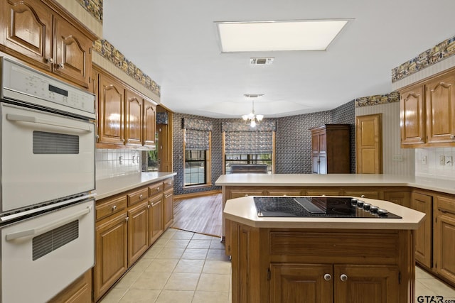 205 Turnberry Cir, Mount Pleasant, TX 75455 - kitchen featuring white double oven, wallpapered walls, black electric cooktop, a peninsula, and light countertops