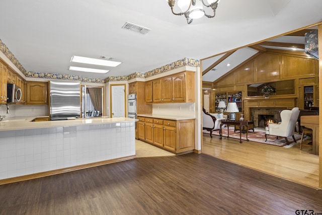 205 Turnberry Cir, Mount Pleasant, TX 75455 - kitchen featuring stainless steel appliances, light countertops, light wood-type flooring, vaulted ceiling, and a chandelier