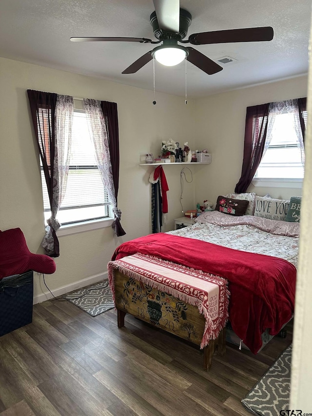 bedroom featuring ceiling fan, dark hardwood / wood-style flooring, and multiple windows