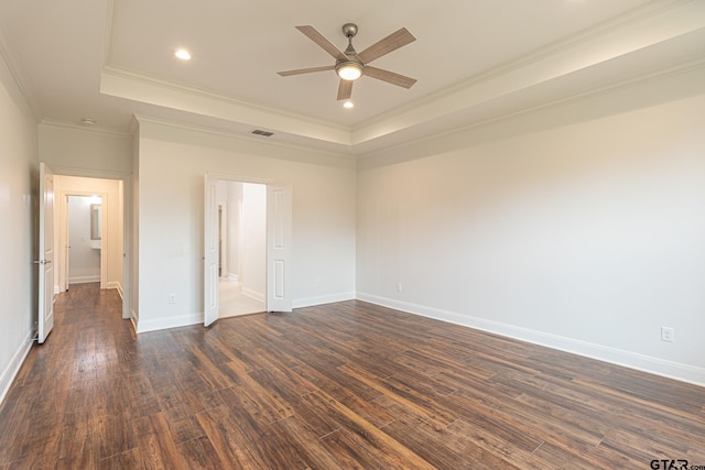 empty room with dark hardwood / wood-style flooring, ceiling fan, crown molding, and a tray ceiling