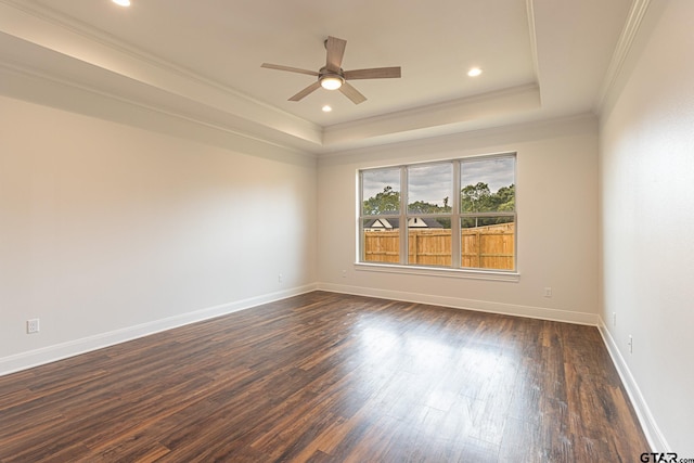 unfurnished room with a raised ceiling, dark wood-type flooring, ceiling fan, and crown molding