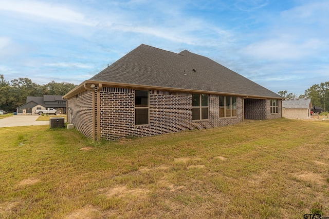 back of house featuring central air condition unit and a yard