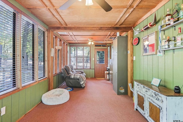 sitting room featuring ceiling fan, light carpet, wooden ceiling, beamed ceiling, and wood walls