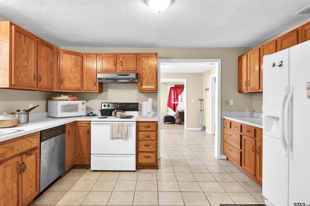 kitchen with light tile patterned floors, white appliances, and a textured ceiling