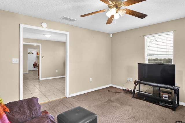 living room with light tile patterned flooring, ceiling fan, and a textured ceiling