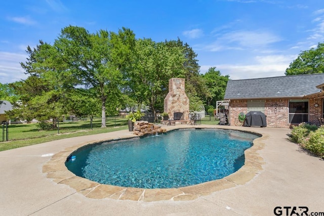 pool with a patio area, exterior fireplace, and fence