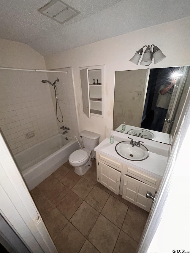 full bathroom with vanity, tiled shower / bath, tile patterned flooring, toilet, and a textured ceiling