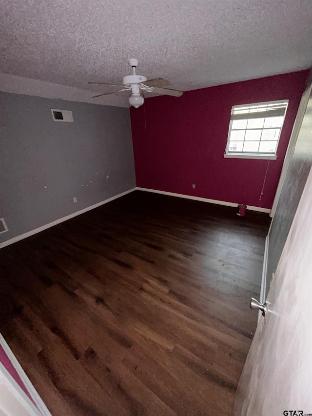 empty room with a textured ceiling, ceiling fan, and dark wood-type flooring