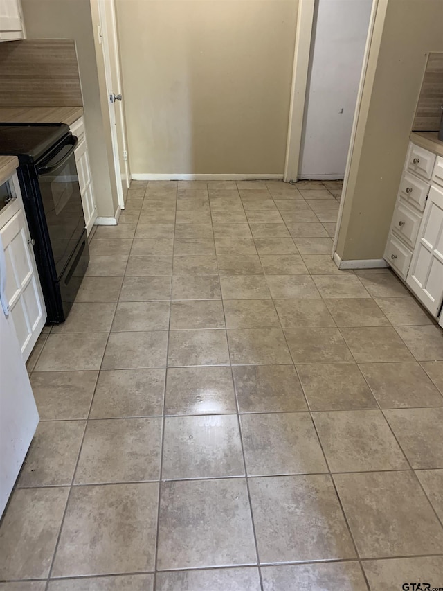 kitchen with white cabinets, black range with electric stovetop, and light tile patterned flooring