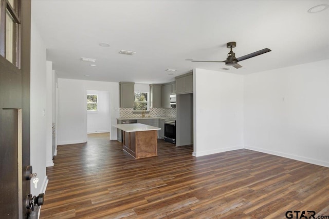 kitchen featuring dark wood-style floors, gray cabinets, a center island, and backsplash