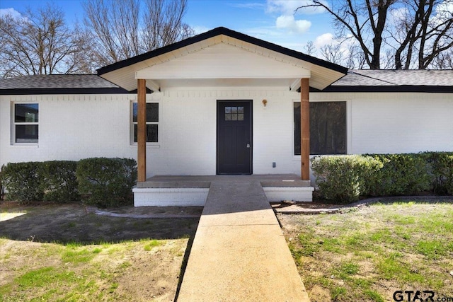 view of front of home with brick siding and a shingled roof