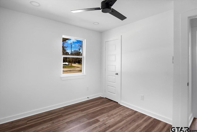 empty room with dark wood finished floors, baseboards, and ceiling fan