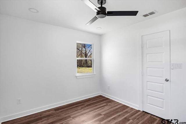 spare room with dark wood-style floors, visible vents, a ceiling fan, and baseboards