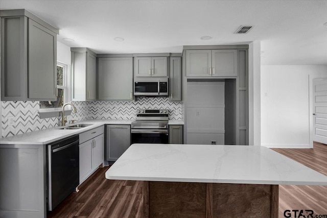 kitchen featuring visible vents, gray cabinets, stainless steel appliances, and a sink