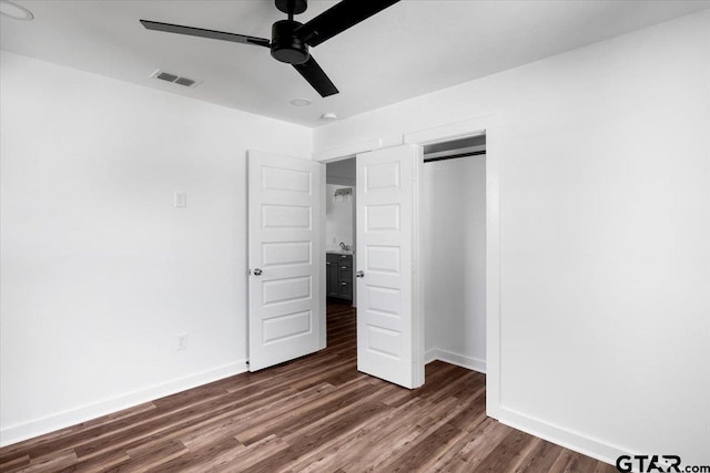 unfurnished bedroom with dark wood-style floors, visible vents, a closet, and baseboards