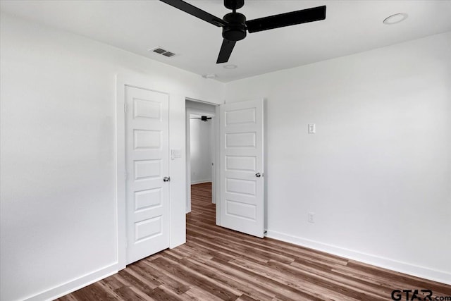 unfurnished bedroom with visible vents, ceiling fan, baseboards, and wood finished floors