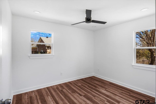 spare room featuring plenty of natural light, a ceiling fan, dark wood-type flooring, and baseboards