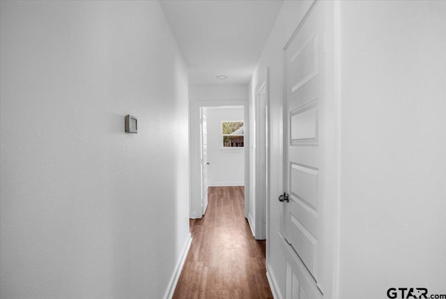 hallway featuring baseboards and dark wood finished floors