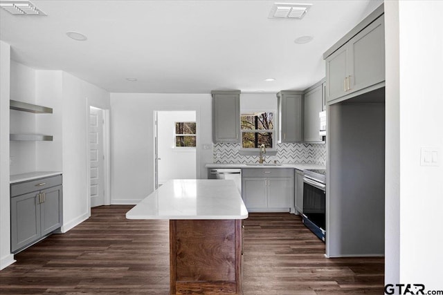 kitchen featuring visible vents, gray cabinetry, a sink, dark wood-style floors, and stainless steel appliances