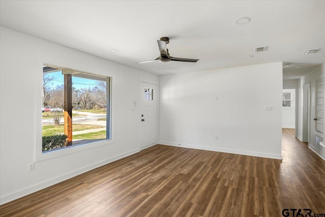 unfurnished room with a ceiling fan, wood finished floors, visible vents, and baseboards