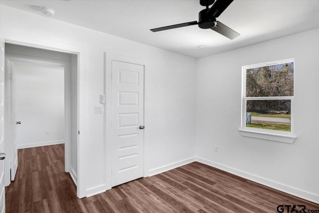 interior space featuring baseboards, a ceiling fan, and dark wood-style flooring