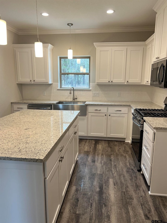 kitchen with white cabinetry, appliances with stainless steel finishes, dark hardwood / wood-style floors, hanging light fixtures, and sink