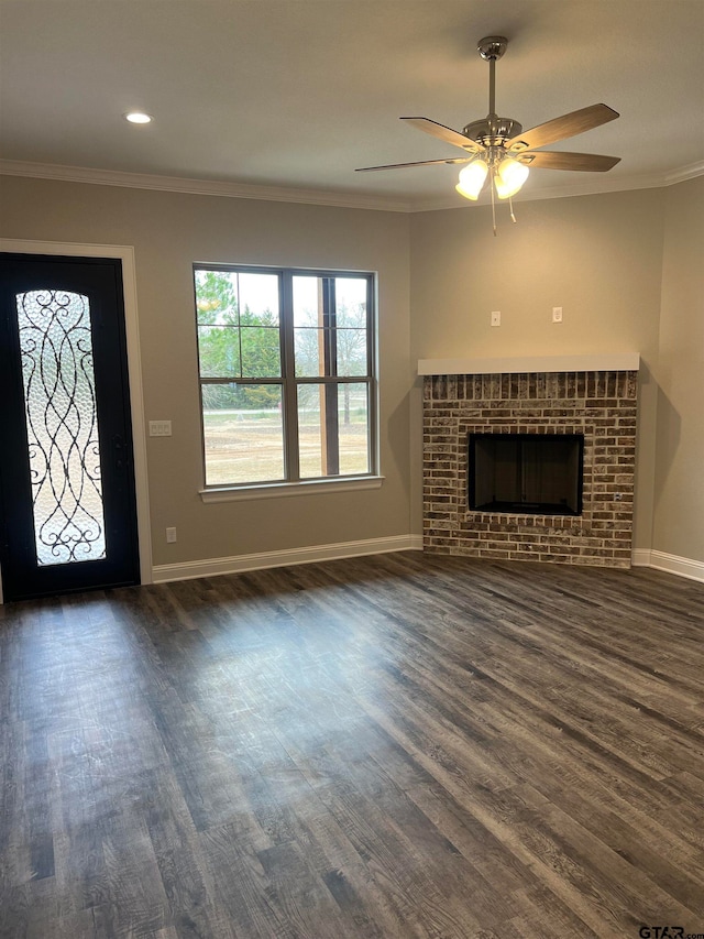 unfurnished living room featuring dark wood-type flooring, a brick fireplace, and ornamental molding