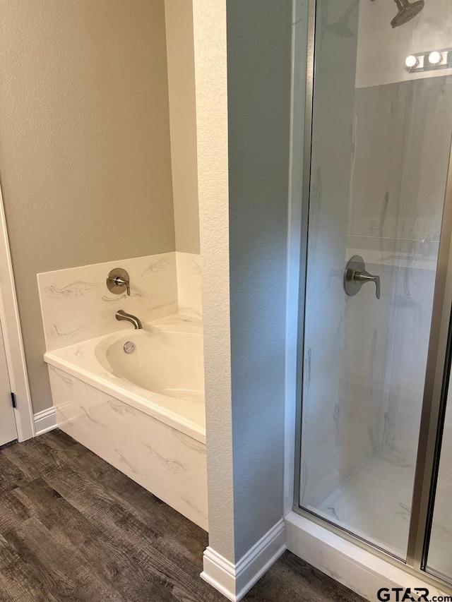 bathroom with hardwood / wood-style flooring and shower with separate bathtub