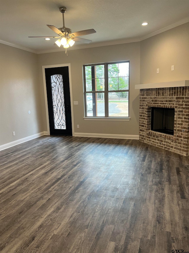 foyer featuring dark wood-type flooring, ceiling fan, a brick fireplace, and crown molding