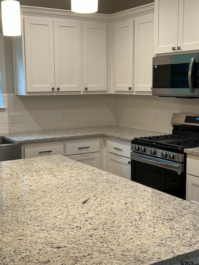 kitchen featuring white cabinetry, appliances with stainless steel finishes, light stone counters, and backsplash