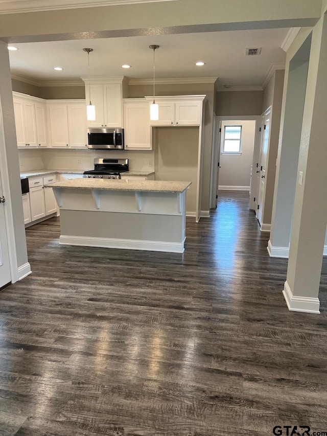 kitchen with a center island, white cabinets, dark hardwood / wood-style floors, pendant lighting, and appliances with stainless steel finishes