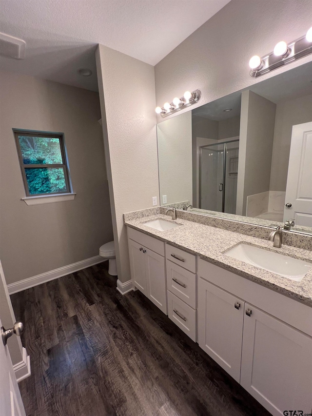 bathroom with a shower with door, vanity, a textured ceiling, hardwood / wood-style floors, and toilet